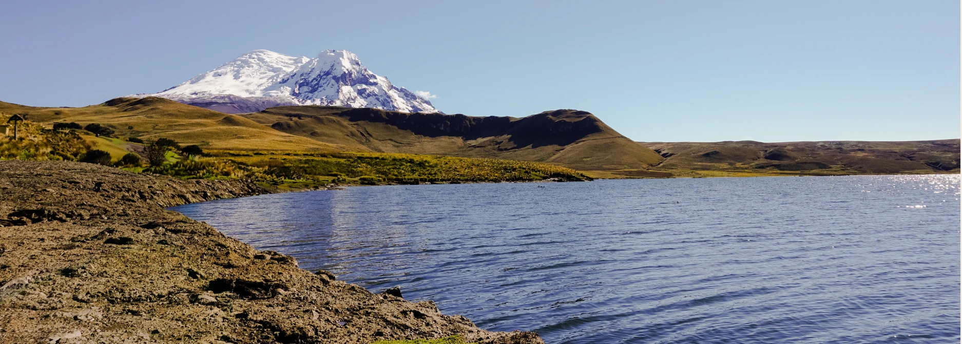 A snow-capped Andean mountain beyond a highland lake